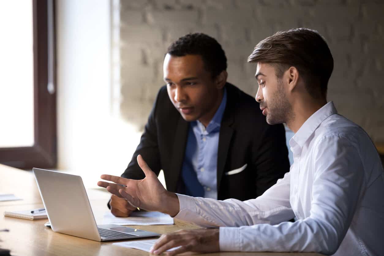 two male solicitors discussing in front of a laptop screen
